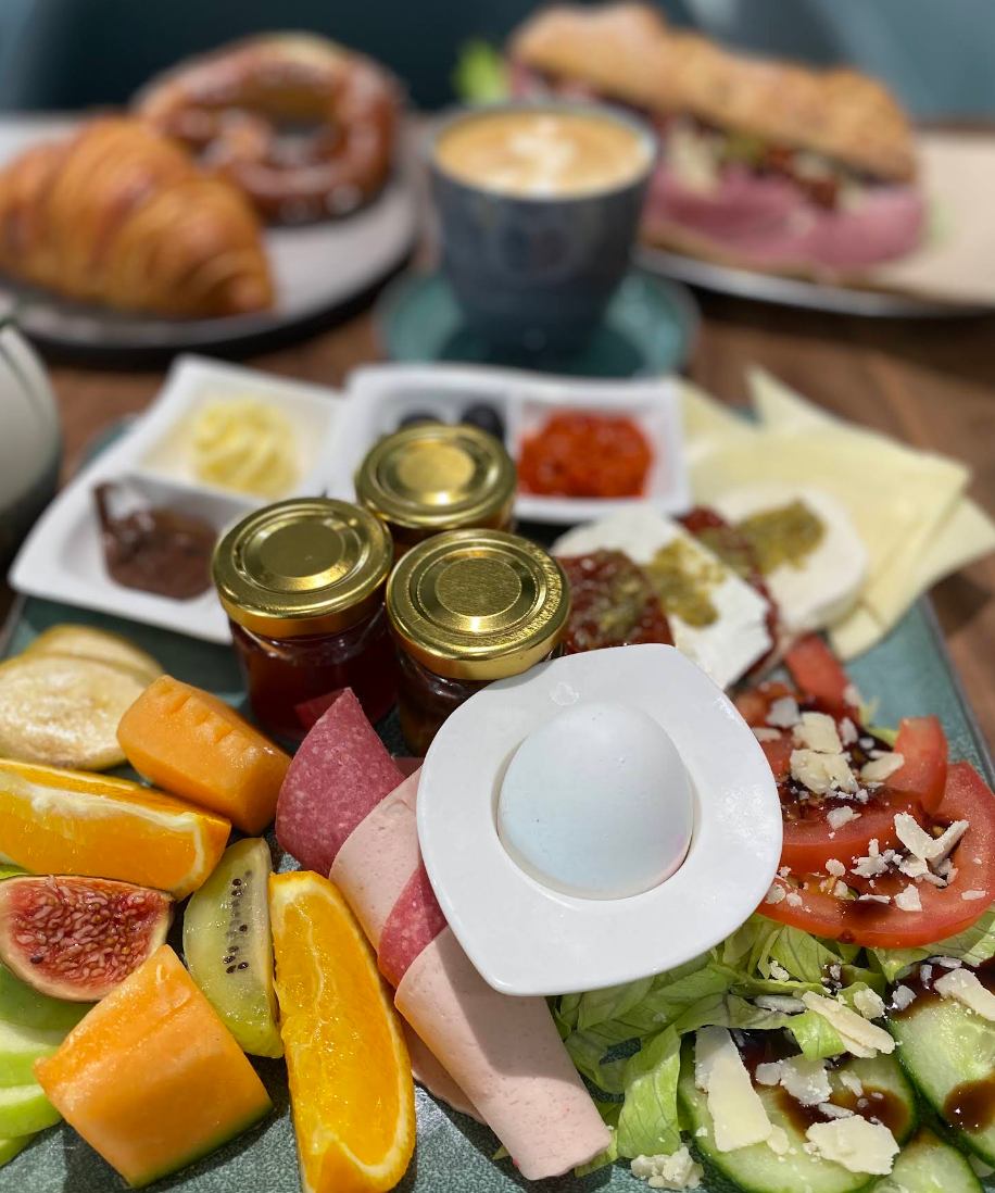 Frühstücksplatte mit Ei, Käse, Aufschnitt, Obst und Marmelade